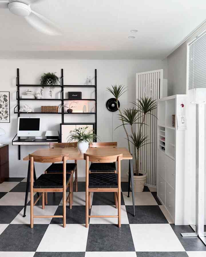 White and wood tone living and dining room featuring wooden dining table and chairs, plants, and wall shelves in a natural modern style