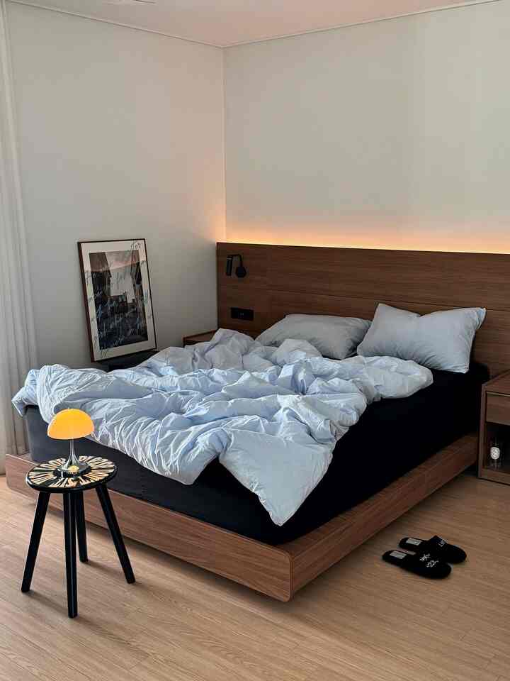 木目調の寝室、ウォルナットのベッドとスカイブルーの掛け布団カバーが調和したホテルライクなインテリア