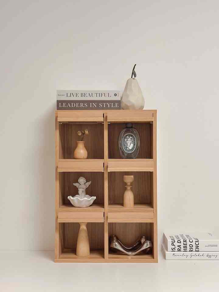 ナチュラルなウッドトーンの6つの仕切りがあるミニ収納キャビネットがベージュの壁の前に置かれた、シンプルで上品な印象の棚のあるインテリア