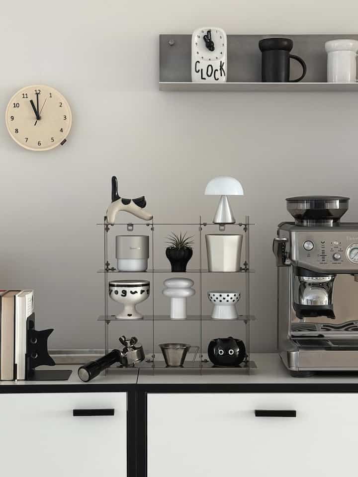 Modern kitchen home cafe with gray wall and white shelves, featuring stainless steel coffee machine and cup rack as focal points