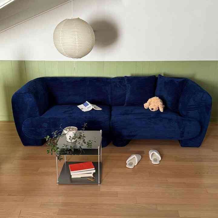 ネイビーのコーデュロイソファとウッドトーンの床が調和するモダンなリビングインテリア