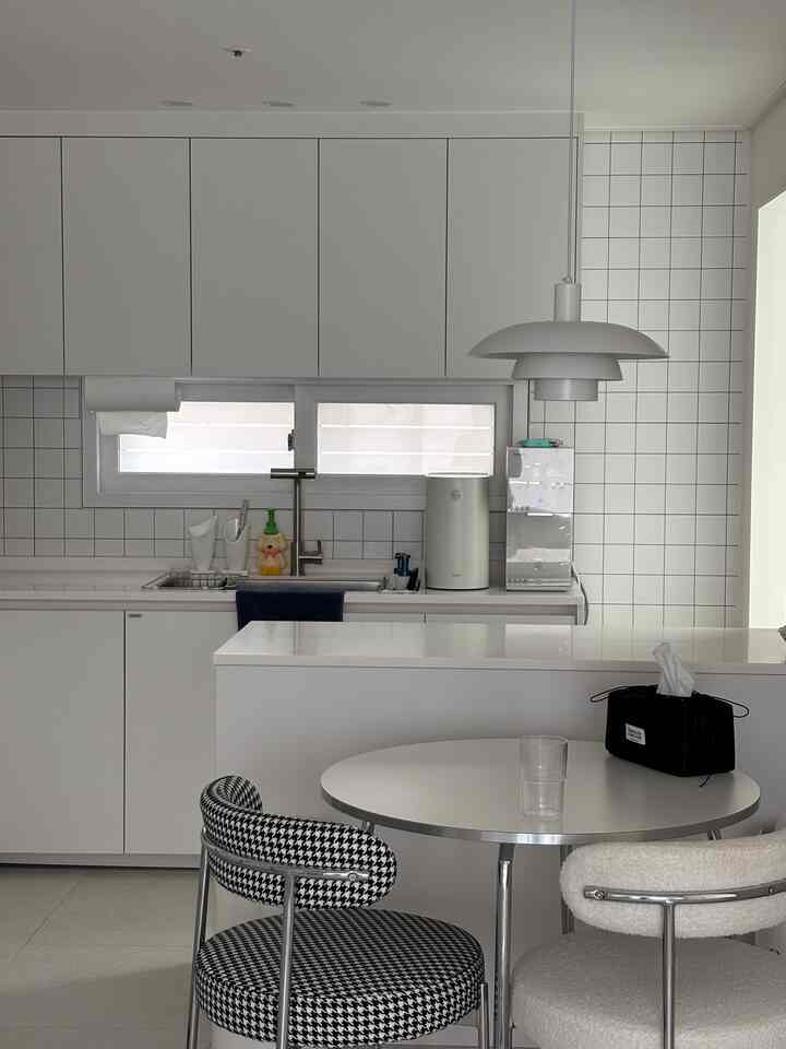 白を基調としたミッドセンチュリーモダンな椅子が配置された、清潔感のあるキッチンのインテリア
