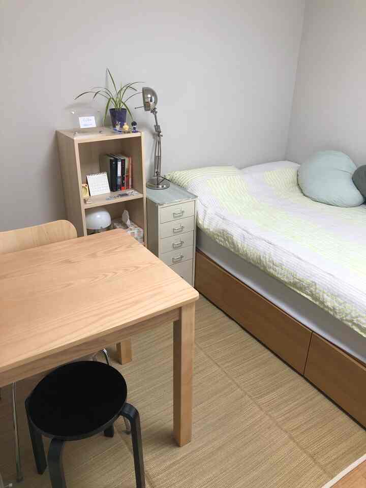 白い壁とライトブラウンの木製家具が調和する、居心地の良い一人暮らしの寝室