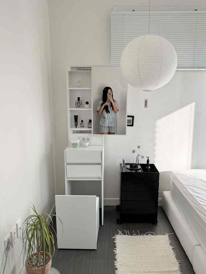 白と黒のトーンの寝室、スライディングミラーの化粧台とトロリー、収納スツールが配置された雰囲気のあるインテリア