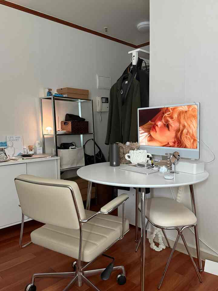 白と茶色のトーンの小さなホームオフィス、オフィスチェアと円形のデスクにコンピューターが配置された整然としたレイアウト