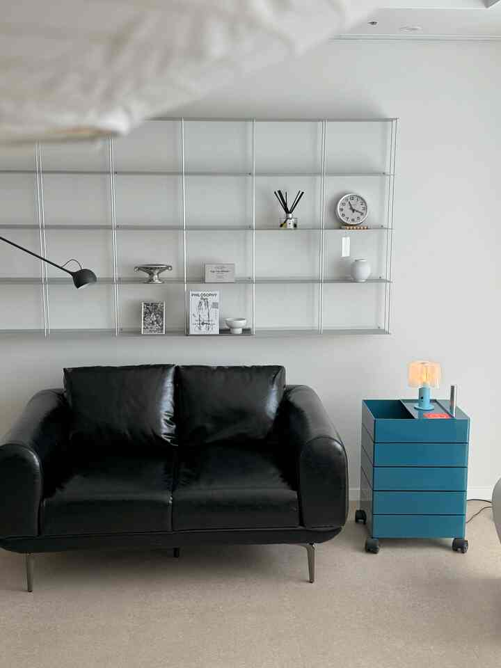 ホワイトトーンのモダンなリビングルームにブラックのソファとブルーのサイドテーブルが配置されたインテリア