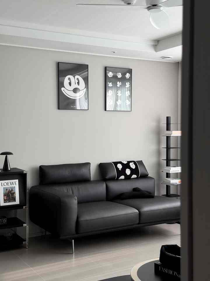 モノトーンのリビング、黒いレザーソファと額縁が配置された印象的な空間