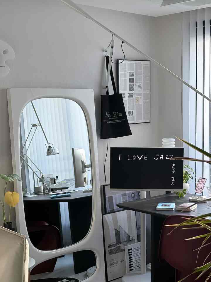 白と黒のトーンが調和するホームオフィス、大きな鏡と植物が配されたシンプルでモダンなインテリア