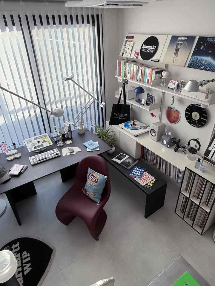 白い壁と黒いデスク、ボルドーカラーのパントンチェアが配置されたモダンなホームオフィスとリスニングルーム