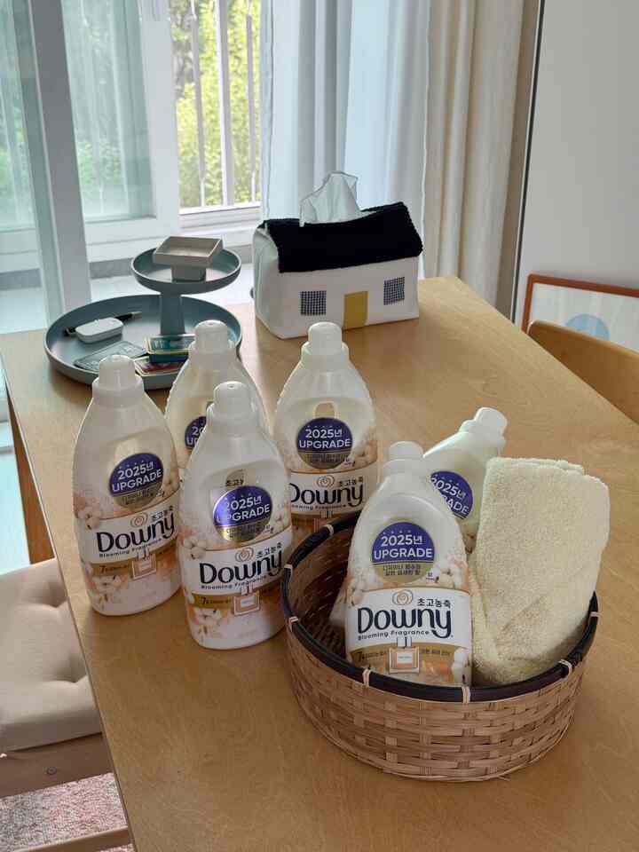 木目調のダイニングルーム、木製テーブルの上にファブリックのティッシュケースと複数のダウニー洗濯用洗剤が配置された清潔な空間