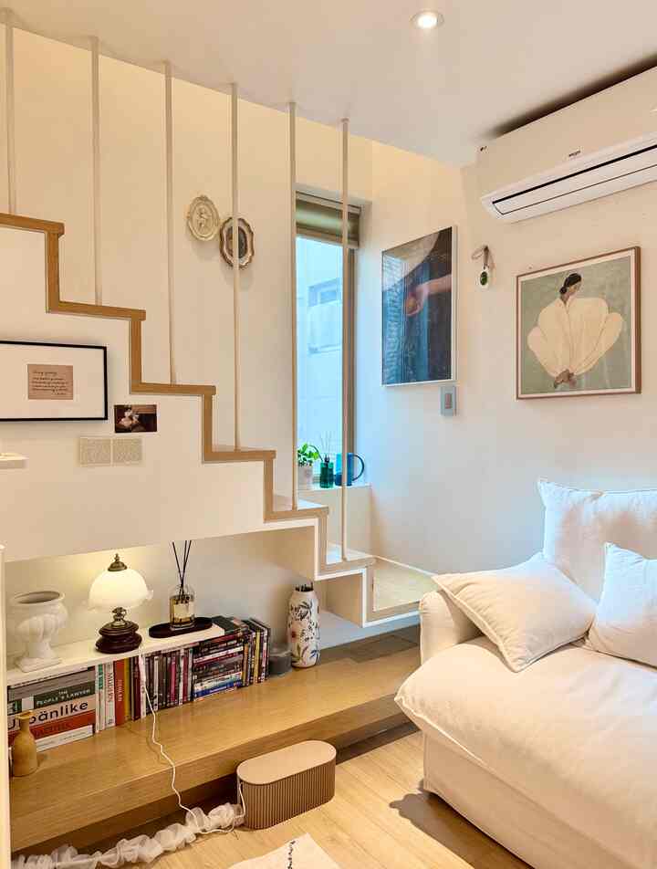 ホワイトと木目調が調和したリビング、ソファと階段下の棚が配置された印象的でシンプルな空間