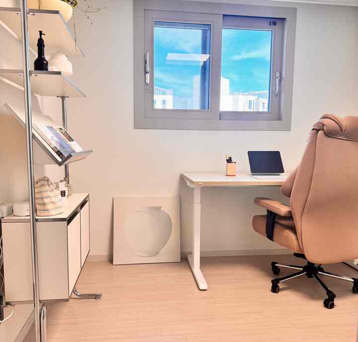 白い壁とベージュのオフィスチェアが配置されたコンパクトなホームオフィスの印象的な空間