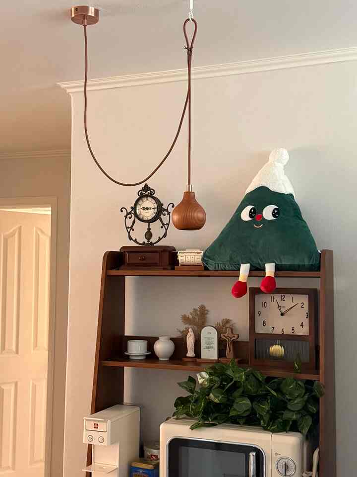 ナチュラルな木目調収納棚とヴィンテージ時計が配置されたキッチン、すりガラスの引き出しとペンダントライトが調和した雰囲気のあるおうちカフェ空間