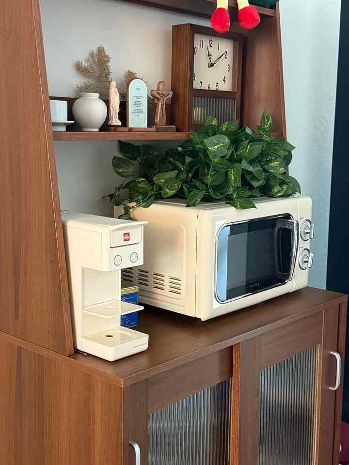 ブラウンの木目調家具とクリーム色のヴィンテージ家電、緑の植物が調和した温かみのあるキッチン空間