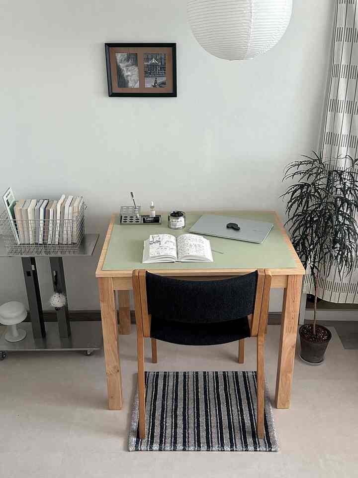 淡い木目調とグレーのシンプルでモダンな一人用ホームオフィス空間、デスクと椅子、テーブルクロスと本棚が配置されたインテリア