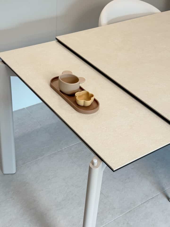 ベージュのダイニングテーブルと白いダイニングチェアがある清潔なキッチンスペース