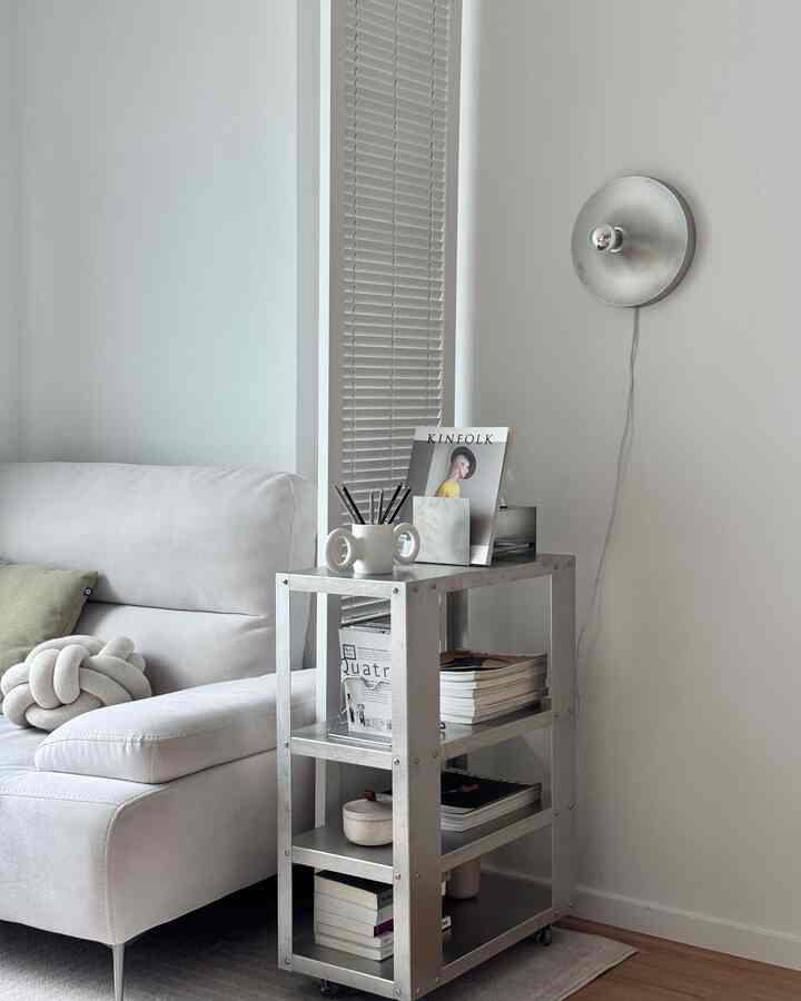 白を基調としたリビング、中央にシルバーのアルミ製トロリー、左側に白いソファが配置された洗練されたモダン空間