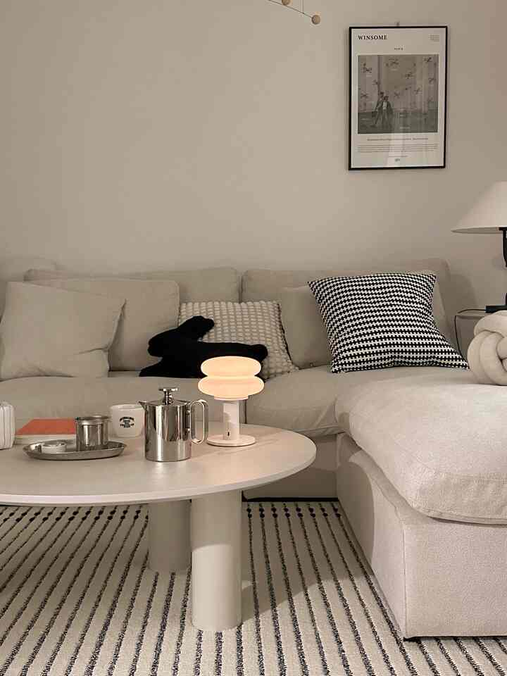 ベージュとホワイトのトーンのリビング、広いコーナーソファとラウンドコーヒーテーブルが調和したシンプルでモダンなインテリア