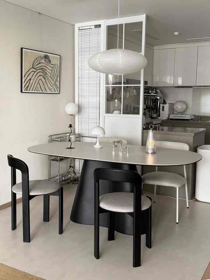 モダンで清潔感のあるキッチン空間、黒い脚とセラミック天板の丸いダイニングテーブルと椅子が配置された洗練されたインテリア