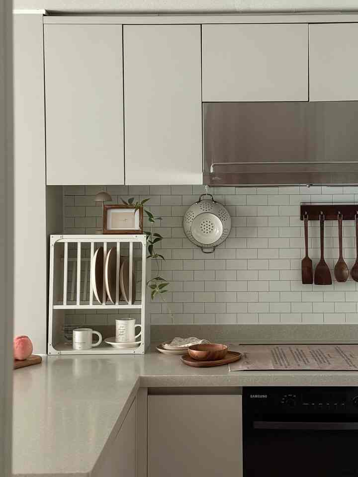 ホワイトとナチュラルカラーが調和するキッチン、すっきりとしたホワイトのキッチンラックと木製アクセサリーが配置されたシンプルで開放感のあるインテリア