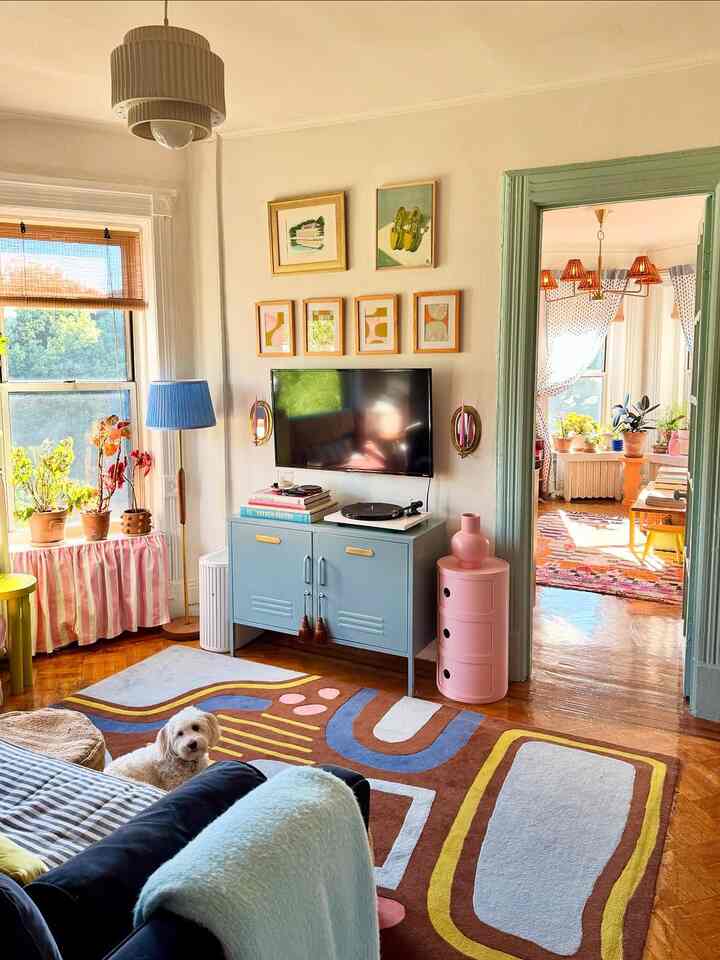 Cozy living room with warm natural light, colorful rug, plants, and modern-retro furnishings