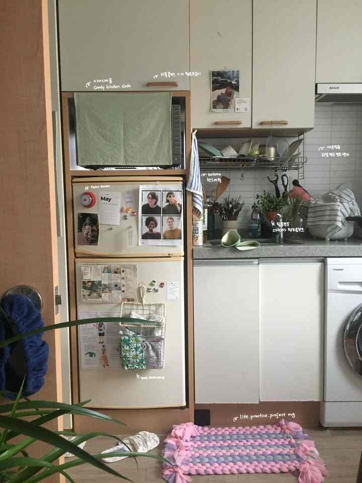 ナチュラルカラーとホワイトトーンのコンパクトなキッチン、冷蔵庫やキッチンタオル、植物が配された赤ちゃんと暮らす空間