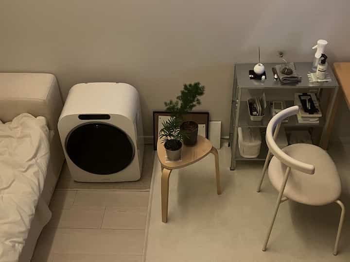 Natural toned small bedroom featuring a bed, wooden stool with plants creating a cozy space