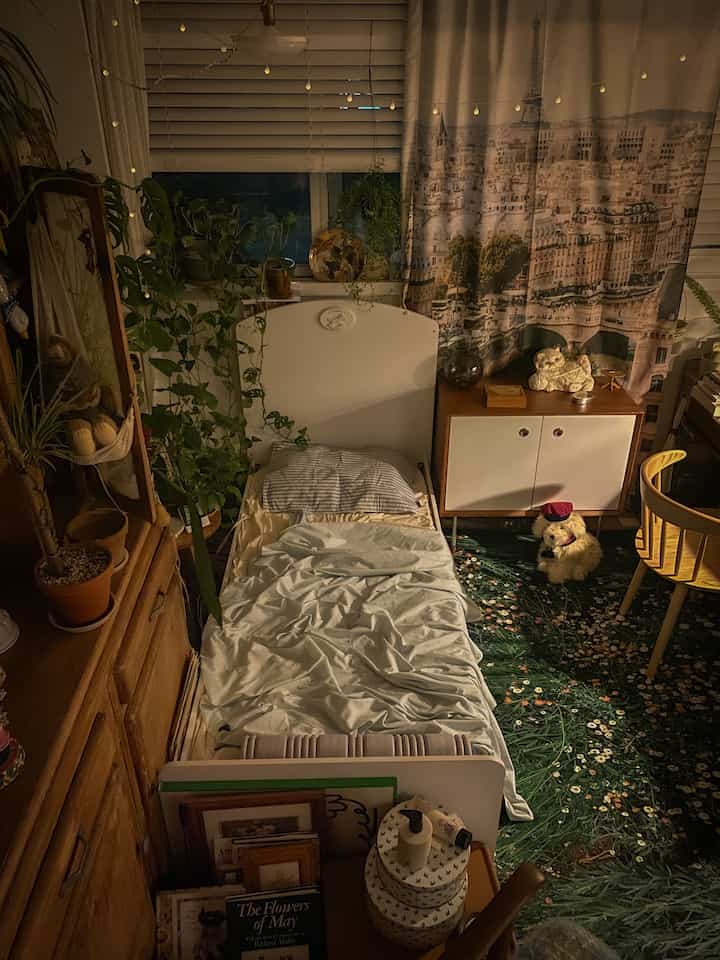 ナチュラルトーンの寝室、白いベッドと木製家具、植物が配置された雰囲気のあるヴィンテージスタイルの空間