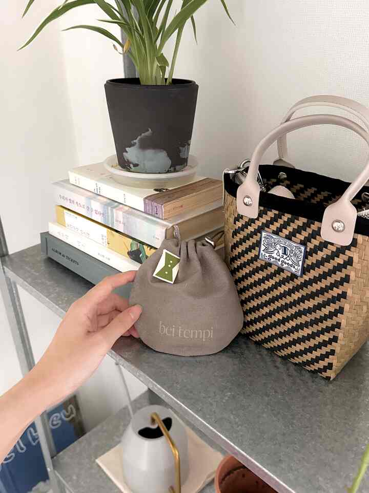 落ち着いた色調の収納棚と植物、ブラウンのバッグが置かれた整った空間の一部