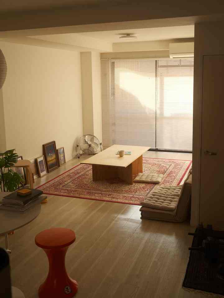 ベージュと赤の色調のリビング、中央に低い木製テーブルとクッションが配されたナチュラルモダンなインテリア