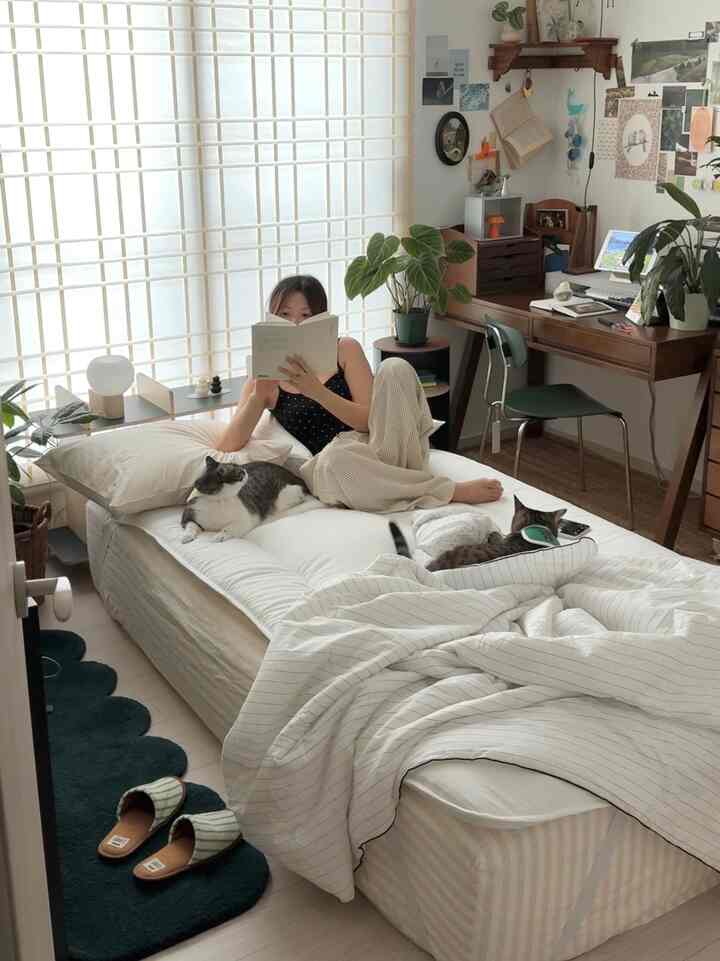 Bright white and wood-tone bedroom featuring a desk and indoor plants with a natural modern atmosphere