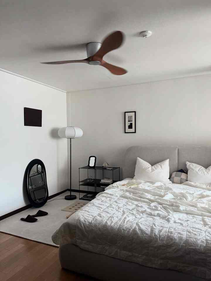 White and natural color bedroom featuring simple bed frame and floor lamp in a modern minimalist setting
