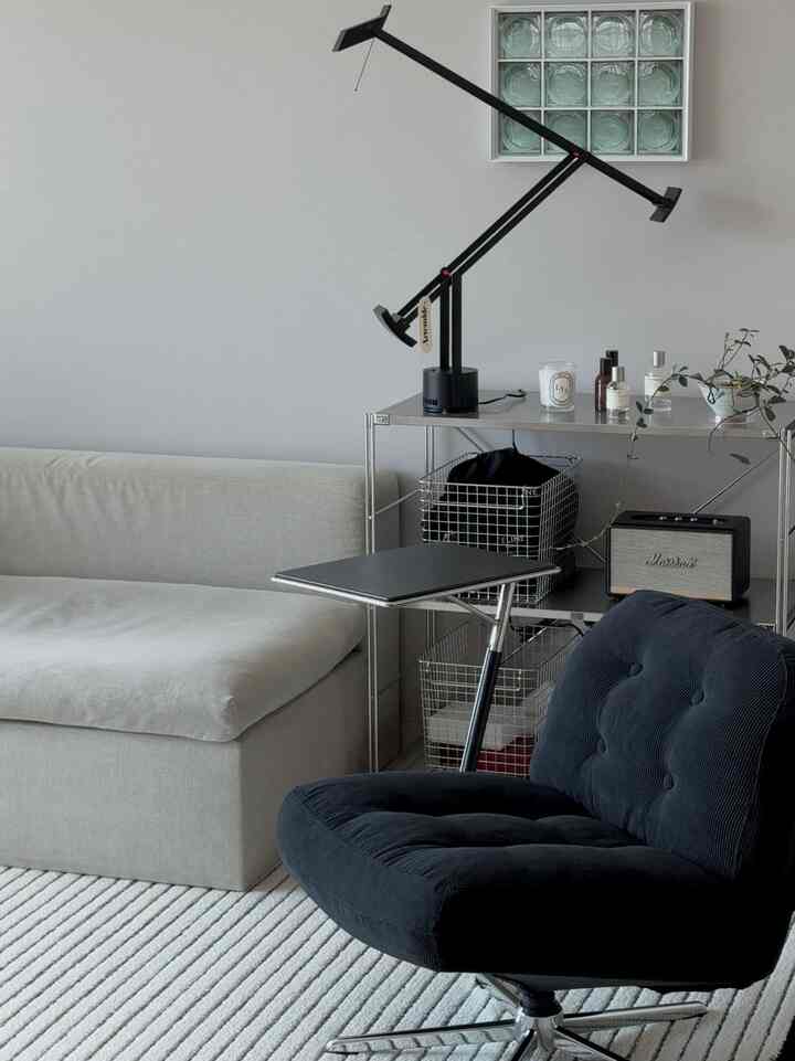 黒とシルバーのトーンが調和するモダンなリビング、シンプルなアームチェアとステンレス棚が配置された洗練された空間