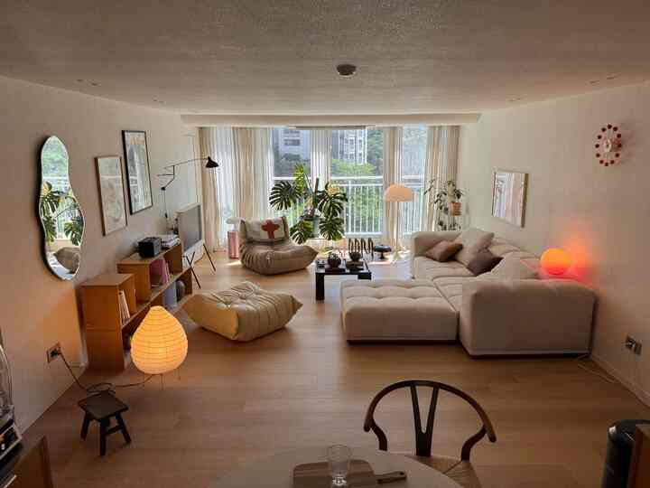 ベージュと木目調のリビング、モダンなソファと植物が配置された落ち着いた雰囲気のインテリア