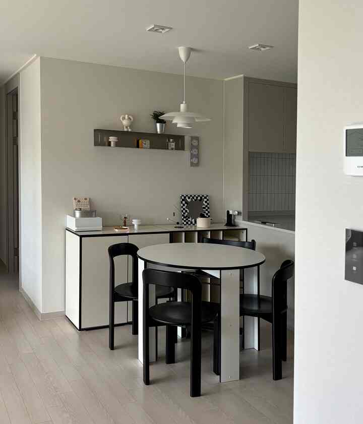 ナチュラルカラーと白を基調とした小さなリビング兼ダイニング、シンプルモダンな丸テーブルと黒い椅子が配置されたインテリア。