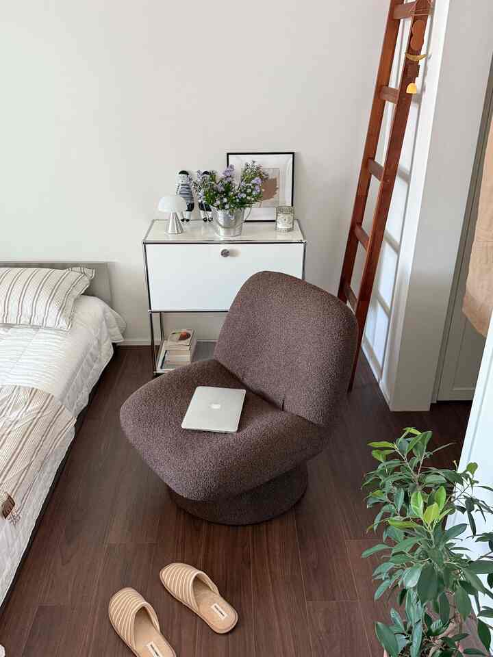 Natural style bedroom with white walls and brown wood floor featuring an armchair and bed in a cozy single household space