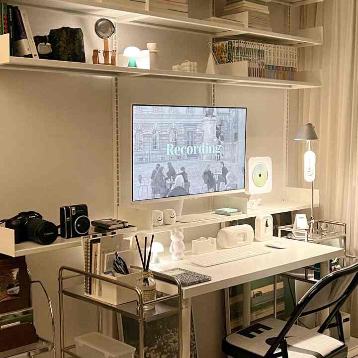 白を基調としたホームオフィス、モニターとシステム棚が配置された整頓された作業空間