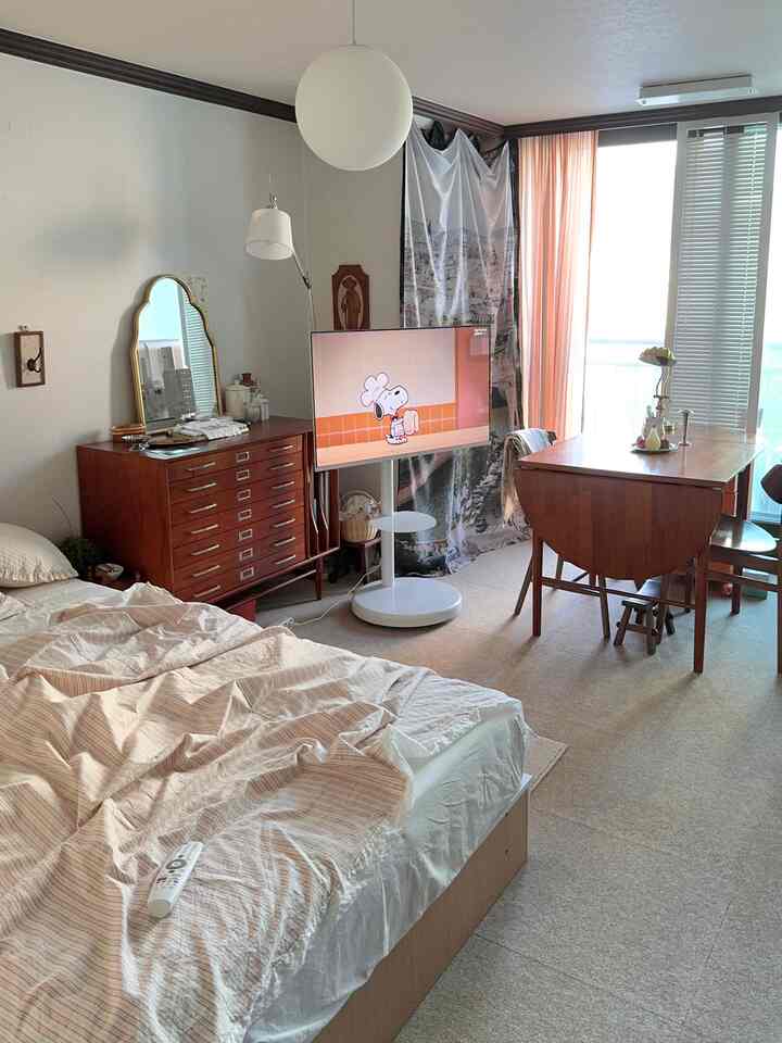 ナチュラルなウッドトーンとベージュの寝室、ミニマルで居心地の良いベッドとダイニングテーブルが配置された印象的な空間