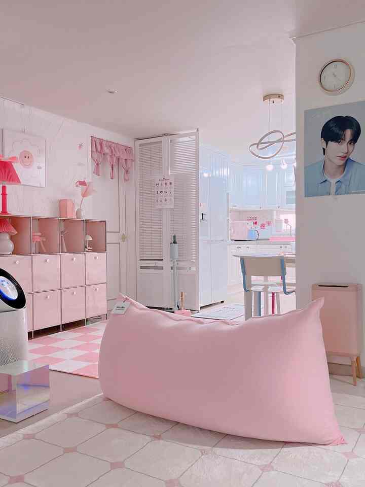 柔らかなピンク色調のリビングとキッチン、ビーンバッグソファとピンクの収納が配置された落ち着いたシンプルなインテリア