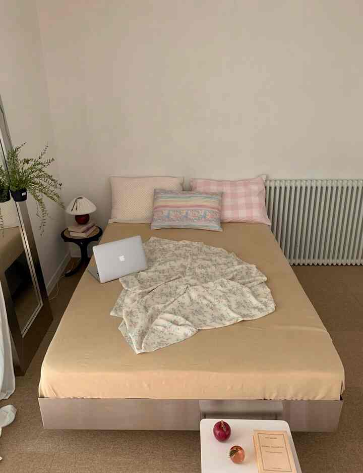 ベージュ色調の寝室、ベッドリネンと枕が配置された自然でモダンな印象のインテリア