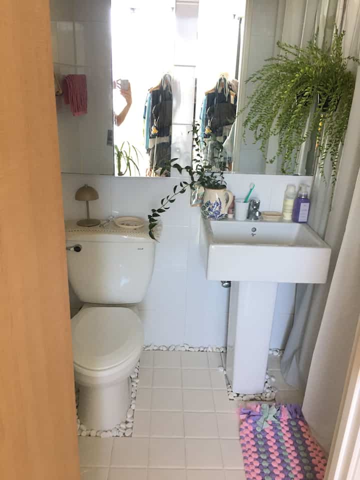 白いタイルと植物が配置されたナチュラルな雰囲気のワンルームバスルーム