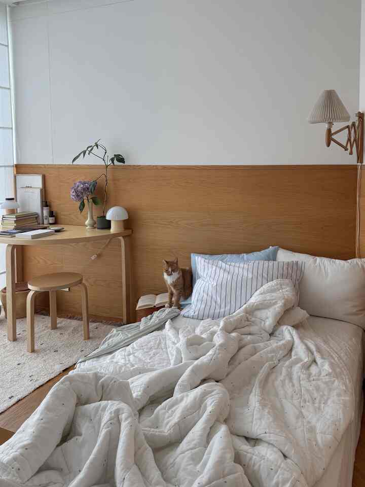 ナチュラルな木目調と白を基調にした寝室、猫がいる落ち着いた雰囲気のインテリア