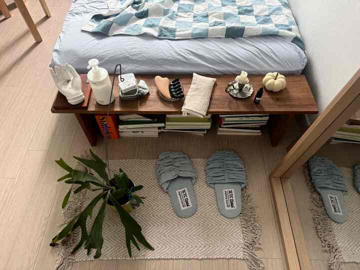 ナチュラルな木目調とホワイトの寝室、ベッドサイドシェルフとスリッパが配された落ち着いた空間