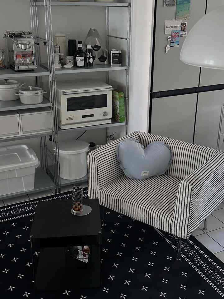 白と黒の色調のキッチンとソファが置かれたコンパクトなワンルーム、すっきりとしたモダンな雰囲気のインテリア