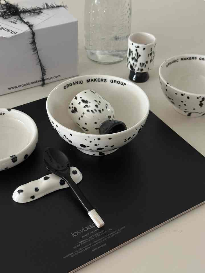 白と黒の斑点があるモダンなダイニングアクセサリーが、黒いランチョンマットの上に配置された白い背景のキッチンスペース