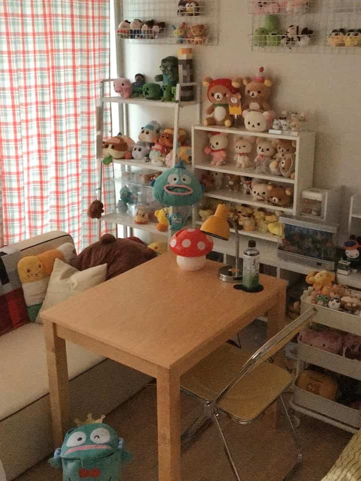 暖かいオレンジ色と木製家具が調和する二人暮らしのオタク部屋、多彩なぬいぐるみと収納が特徴的なかわいらしい空間