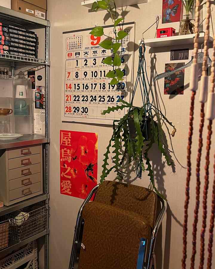 ブラウンの折りたたみ椅子と金属製の棚があり、赤いポスターとカレンダーが配置された居心地のよいレトロな空間の一角