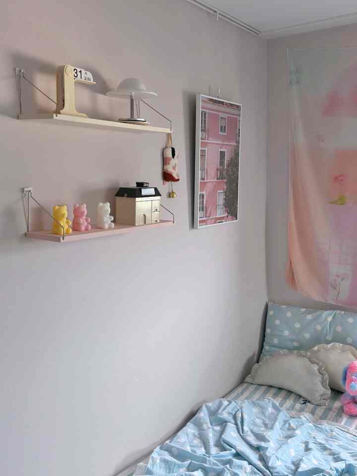 パステル調の子供部屋、壁の棚とかわいい寝具が配置された雰囲気のある空間