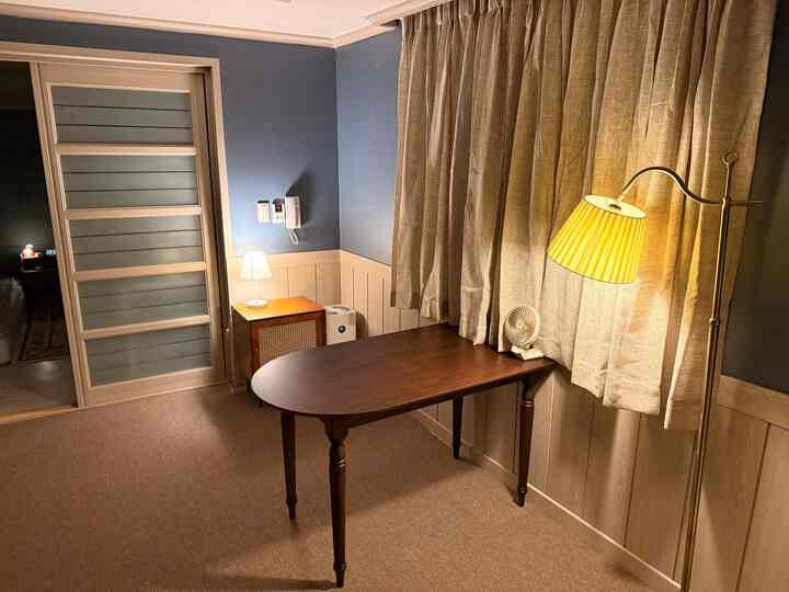 ネイビーブルーの壁とブラウンの家具、柔らかな照明が配置されたコンパクトなリビングルーム