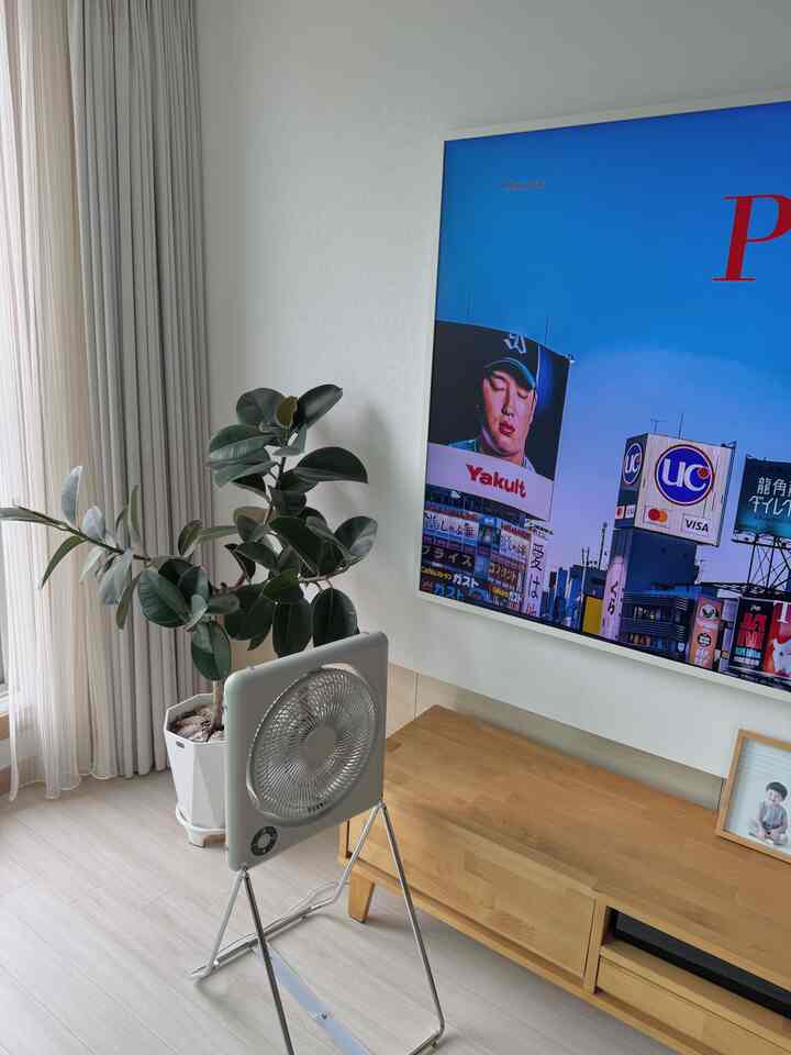 明るくナチュラルなトーンのリビングルーム、サムスンフレームテレビと植物が配置されたミニマルで落ち着いた雰囲気のインテリア